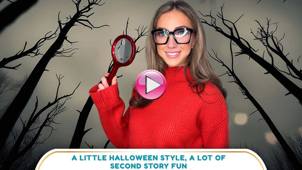 Brooke wears a red sweater and oversized black glasses while holding a magnifying glass for a Velma-inspired Halloween look.