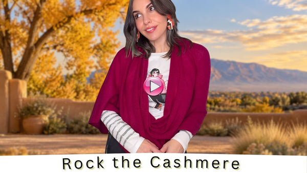 Model wearing a berry cashmere wrap over a graphic tee against a fall New Mexico backdrop with golden trees and the Sandia Mountains.